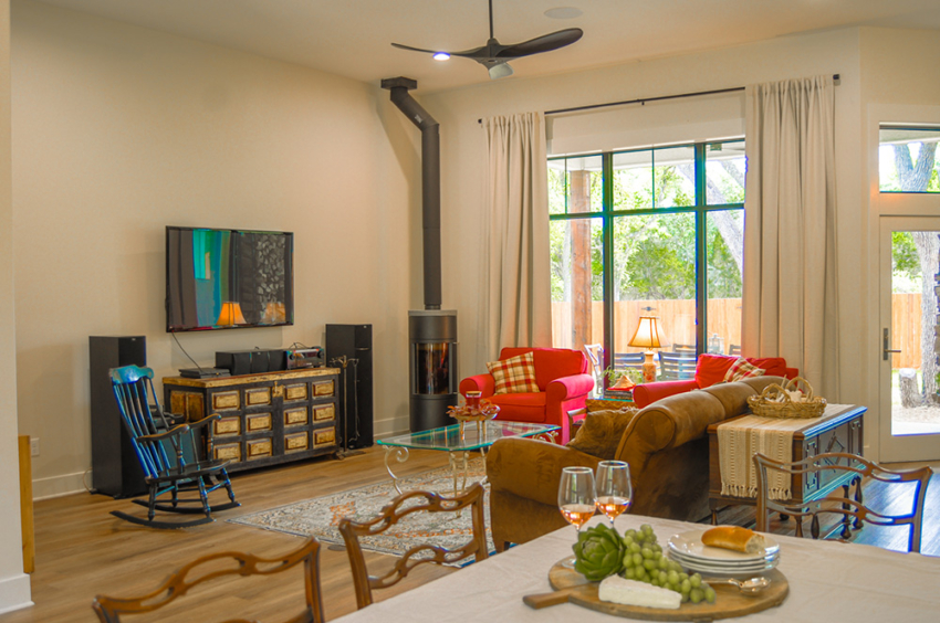 Living room and dining room of custom home built in Woodcreek, Texas but S.B. Thompson Construction. Farmhouse design with dining table, curtained window, and custom fire burning stove.