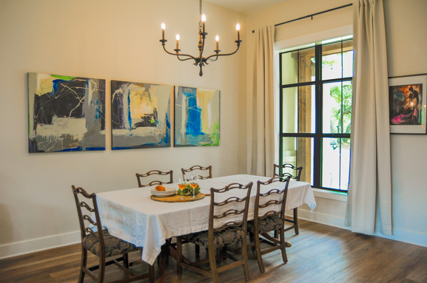 Dining room of custom home built in Woodcreek, Texas but S.B. Thompson Construction. Farmhouse design with large dining table, curtained window, and custom art.