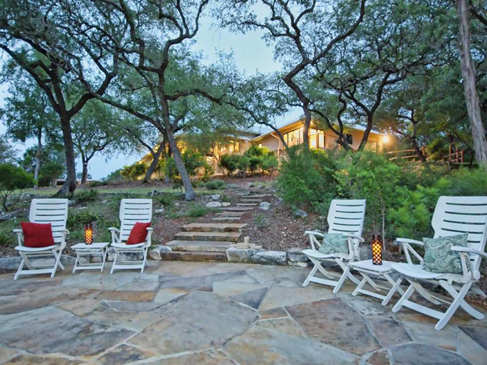 Stone seating area near a fire pit off the back of a custom built on in the Central Texas Hill Country.