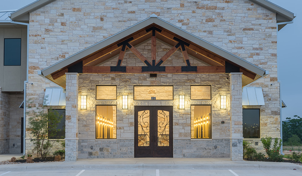 Construction Consulting and contracting in Central Texas. 2 story building with Limestone front and oak beams. Ornate wood, glass, and iron front door.