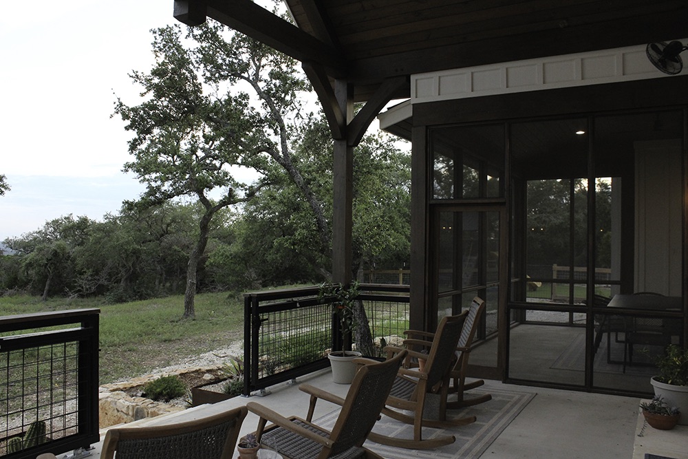 Custom Home black and white built by SB Thompson in Wimberley, Texas. Small minimally landscaped back yard and patio, rock wall. View from the back patio.